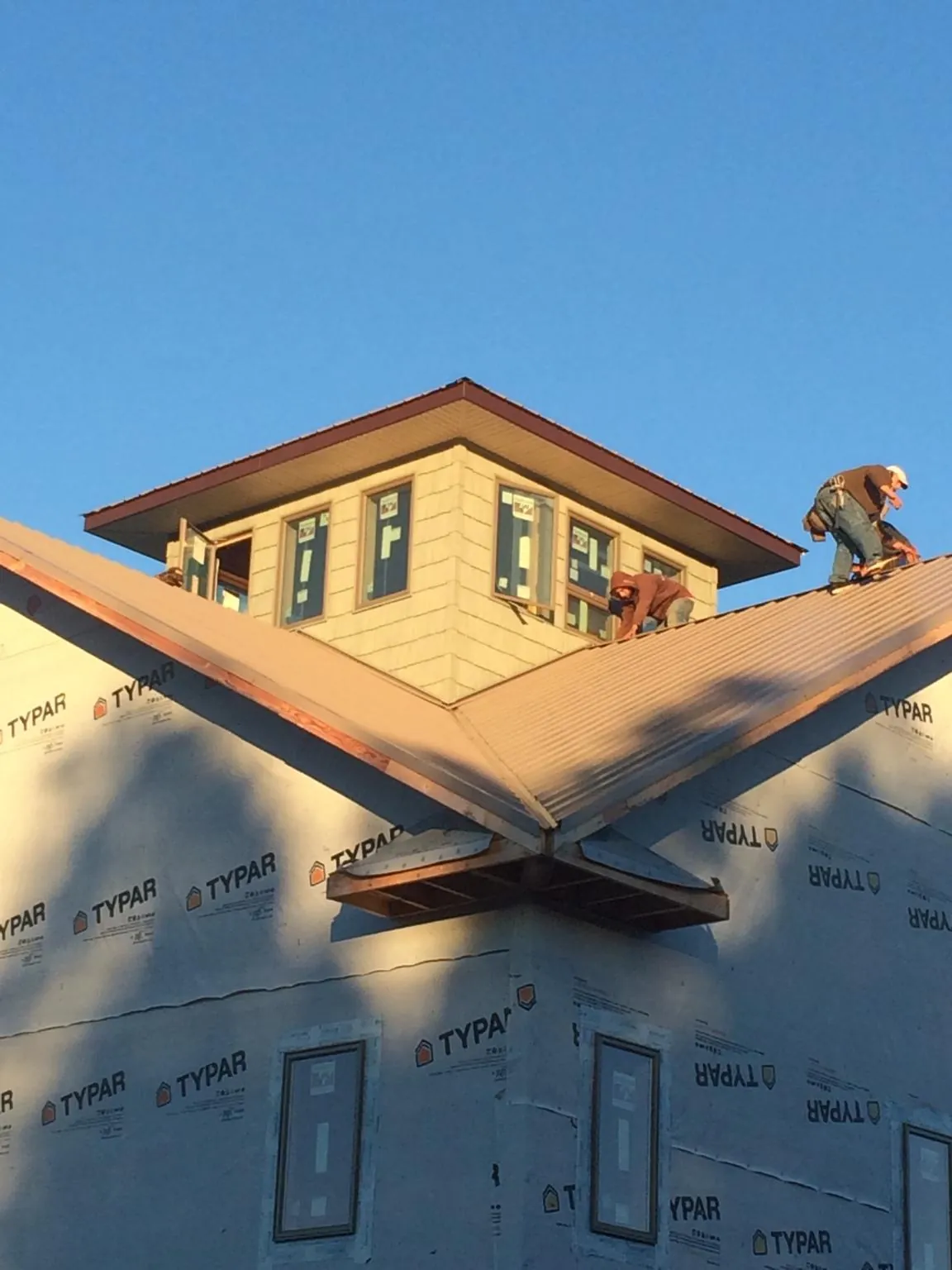 Roofers working around a rooftop cupola on a new metal roof at sunset — Roof Waterproofing in Sherman by Roofing Brothers
